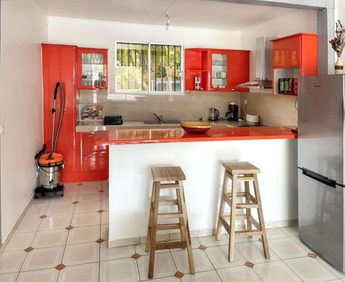 a kitchen with red cabinets and two bar stools at Villa charmante près de Saint-Esprit avec piscine privée in Quartier Monplaisir