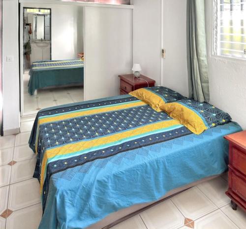 a bed with a blue and yellow comforter in a room at Villa charmante près de Saint-Esprit avec piscine privée in Quartier Monplaisir