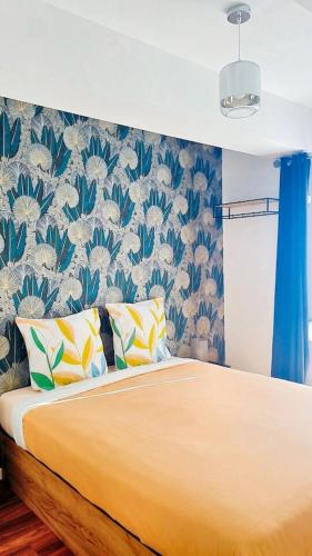 une chambre avec un lit avec un papier peint bleu et blanc dans l'établissement Appartement confortable à Raismes - 60 m², parking privé, à Raismes