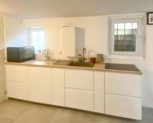 a kitchen with white cabinets and a sink at Appartement cosy à Les Pavillons-sous-Bois 30 m² avec jardin clôturé in Les Pavillons-sous-Bois