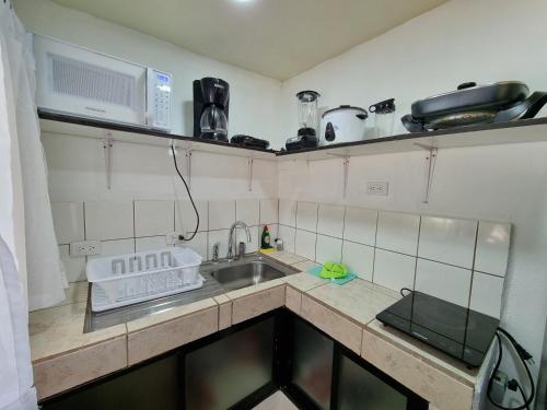 a small kitchen with a sink and a microwave at Pinilla Highlands Incredible mountain views in Tamarindo