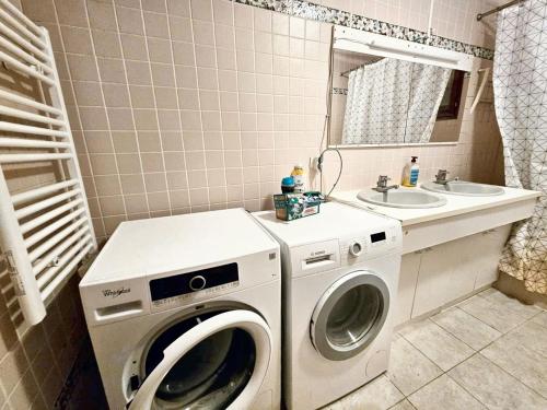 une salle de bain avec une machine à laver et un lavabo dans l'établissement Maison confortable à Péron - Terrasse, à Péron