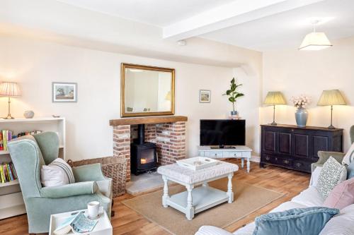 a living room with a fireplace and a tv at Chantry Cottage - Newby Hall, Ripon, North Yorkshire in Copt Hewick