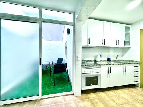 a kitchen with white cabinets and a sliding glass door at Vivienda céntrica cerca de todo in Alicante