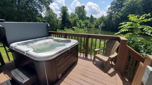 a hot tub sitting on a deck with a chair at Edgewater Escape, Hocking Hills, Hot Tub, Pond in Rockbridge