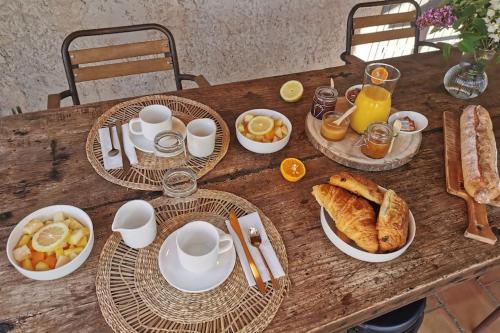 a wooden table with plates of breakfast food on it at L'Atelier de Maison VB in Le Beausset