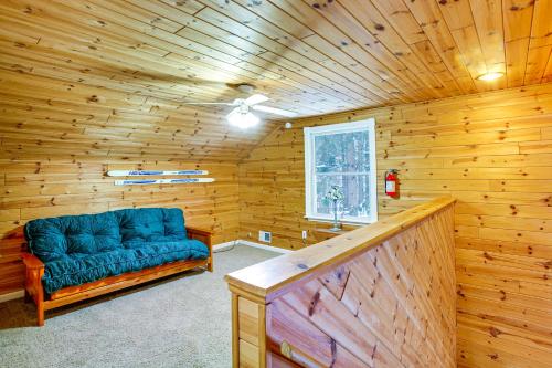 a living room with a blue couch in a wooden room at Less Than 1 Mi to ATV Trails Cadillac Golf Retreat! in Cadillac