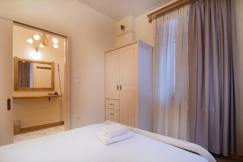 a bedroom with a white bed and a mirror at Sokaki Guesthouse in Arachova