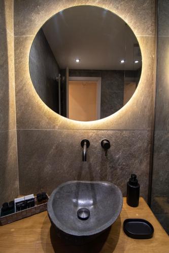 a bathroom with a sink with a round mirror at Sokaki Guesthouse in Arachova