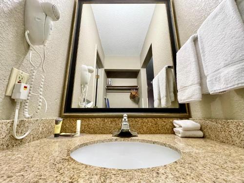 a bathroom sink with a mirror and a phone at FairBridge Inn & Suites Fort Wayne in Fort Wayne