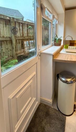 a door in a kitchen with a sink and a window at THE ASH TREE - Charming & comfortable apartment in Frome