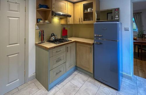 a kitchen with a blue refrigerator and a microwave at THE ASH TREE - Charming & comfortable apartment in Frome