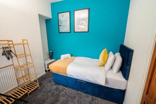 a bedroom with a blue wall and a bed at Stylish 3-Bed Swansea Home with WiFi & Kitchen in Swansea