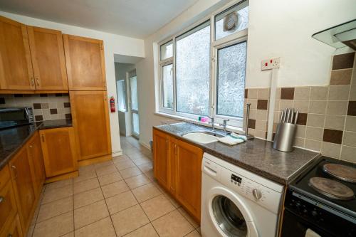 a kitchen with a sink and a washing machine at Stylish 3-Bed Swansea Home with WiFi & Kitchen in Swansea