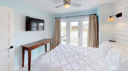 a bedroom with a white bed and a television at BEST BEACH Cottage Two Gorgeous Ocean Views - Renovated Like POTTERY BARN - Beach Steps Away in Saint Augustine Beach