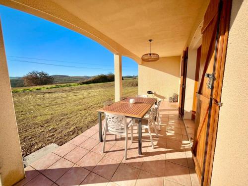 a table and chairs on a patio with a view of a field at Les vallons de Gascogne in Bazian