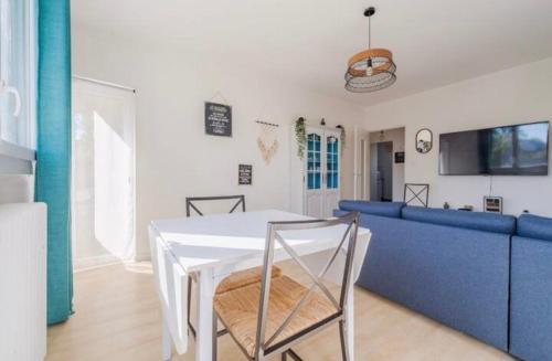 a dining room with a white table and a blue couch at Lumineux, chaleureux et spacieux T2 parking wifi in Toulouse