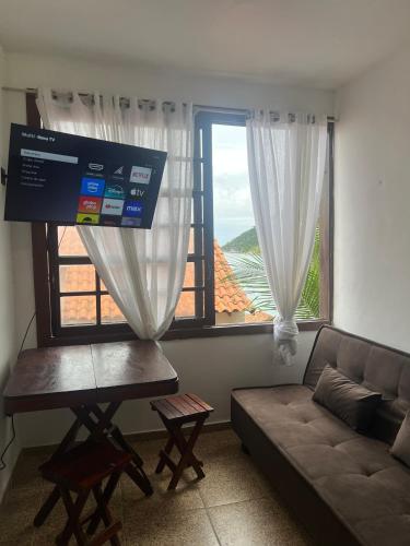 a living room with a couch and a large window at Estalagem pé na areia in Arraial do Cabo