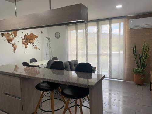 a kitchen with a counter with stools and a table at Apartamento acogedor con vista a la naturaleza in Floridablanca