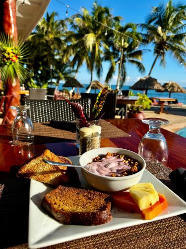a plate with a bowl of food on a table next to the beach at Belizean Dreams Resort in Hopkins