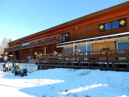 a building with people standing outside of it in the snow at Sport-hotel Šibeniční vrch in Mnichovice