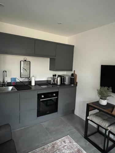 a kitchen with gray cabinets and a sink and a table at The Hideaway - Free Street Parking in Swansea