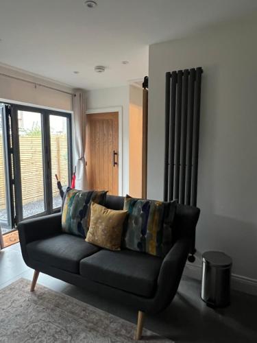 a black couch in a living room with a window at The Hideaway - Free Street Parking in Swansea