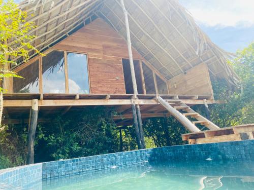 a house with a thatched roof next to a swimming pool at Mamba Yala in Tissamaharama