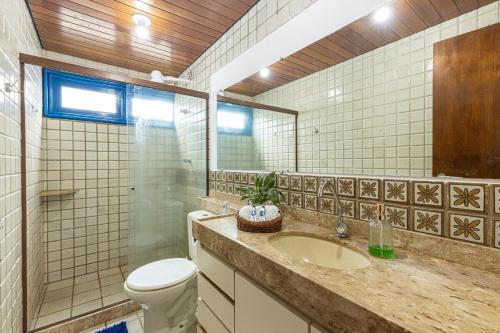 a bathroom with a sink and a toilet and a mirror at Casarão de vidro - Pé na Areia - Praia Enseada dos Corais in Cabo de Santo Agostinho