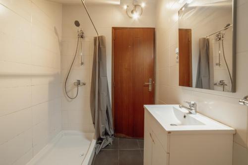 a bathroom with a sink and a shower and a mirror at Pedras Village House by Vacationy in Porto