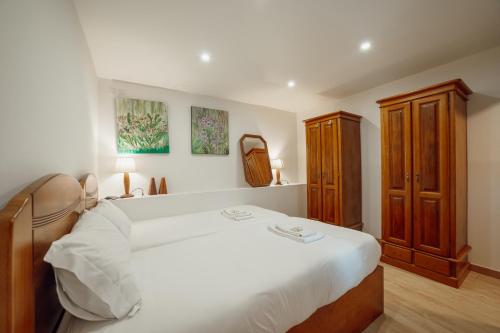 a bedroom with a white bed and a wooden cabinet at Pedras Village House by Vacationy in Porto