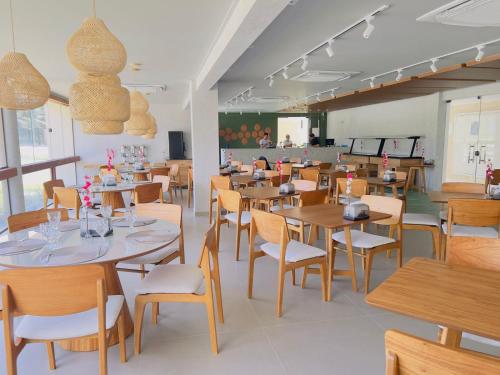 jadalnia z drewnianymi stołami i krzesłami w obiekcie MALIA BEACH - Alto Padrão - PRAIA MURO ALTO - Porto de Galinhas w mieście Porto de Galinhas