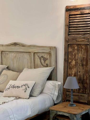 a bed with a wooden headboard and a table with a lamp at Les pondres en vaunage in Caveirac