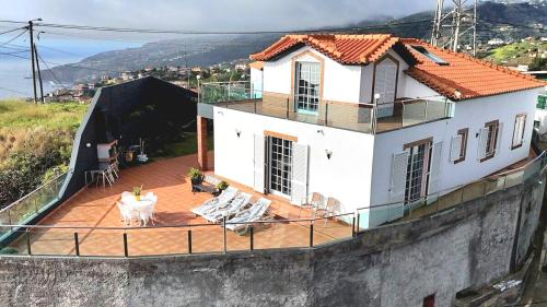 a white house with a deck with chairs at Madeira Island Villa Oceane Ribeira Brava in Ribeira Brava