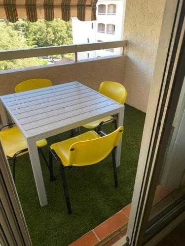 d'une table et de chaises jaunes sur un balcon. dans l'établissement Sainte Maxime, appt tout confort, à Sainte-Maxime