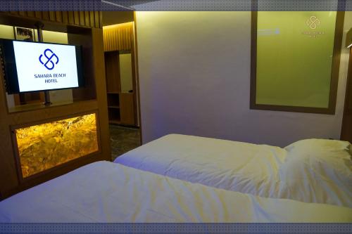 a bedroom with two beds and a flat screen tv at Sahara Beach in Tan-Tan Plage
