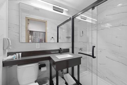 a bathroom with a sink and a glass shower at Hotel TREMONT Bronx Yankee Stadium in Bronx