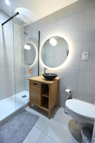 une salle de bain avec un lavabo et un miroir dans l'établissement Marina - charmante maison avec courette, à Langrune-sur-Mer