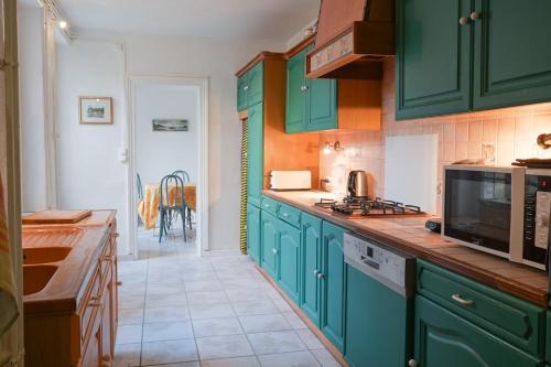 La cuisine est équipée de placards verts et d'un four micro-ondes. dans l'établissement Marina - charmante maison avec courette, à Langrune-sur-Mer