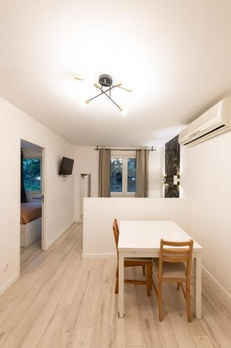 une salle à manger blanche avec une table et des chaises blanches dans l'établissement Appartement Central Lyon 3ème, à Lyon