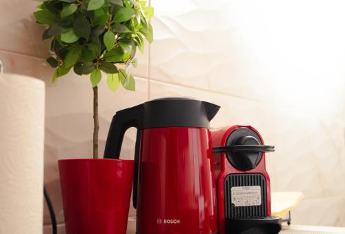 a red coffee maker next to a vase with a plant at Central House in Plaka in Athens