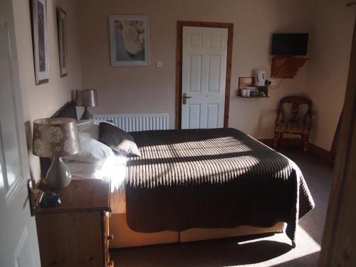 a bedroom with a bed and a table with a lamp at Woodlawn House in Killarney