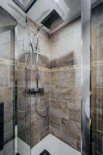 une douche avec une porte vitrée dans une salle de bain dans l'établissement Charmante Maison avec jardin sans vis-à-vis, à Saint-Fons