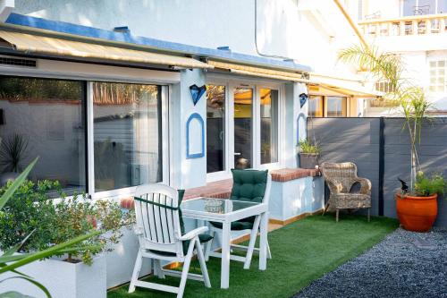 a small patio with a table and chairs on grass at Appartement avec piscine et jacuzzi à 50mètres de la plage et 5min de l'allée des Pins in Argelès-sur-Mer