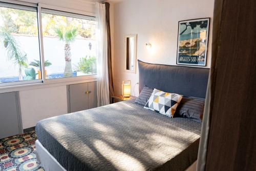 a bedroom with a bed and a large window at Appartement avec piscine et jacuzzi à 50mètres de la plage et 5min de l'allée des Pins in Argelès-sur-Mer