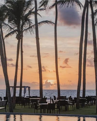 a group of tables and palm trees on the beach at Flat Recanto Muro Alto - Porto de Galinhas in Ipojuca