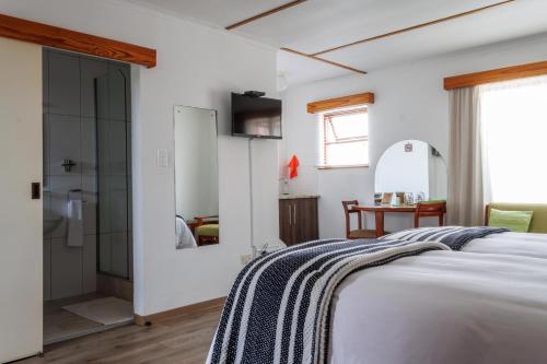 a white bedroom with a bed and a bathroom at Haus Garnison B&B in Swakopmund