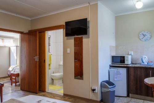 a bathroom with a toilet and a tv on the wall at Haus Garnison B&B in Swakopmund