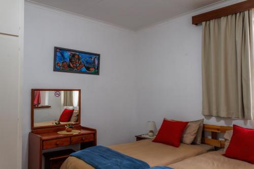 a bedroom with a bed and a mirror and a bed sidx sidx sidx at Haus Garnison B&B in Swakopmund