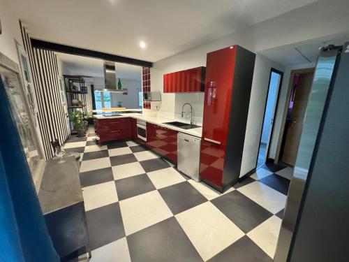 une cuisine avec des placards rouges et un sol en damier dans l'établissement maison loft au pied du Luberon, à Cavaillon